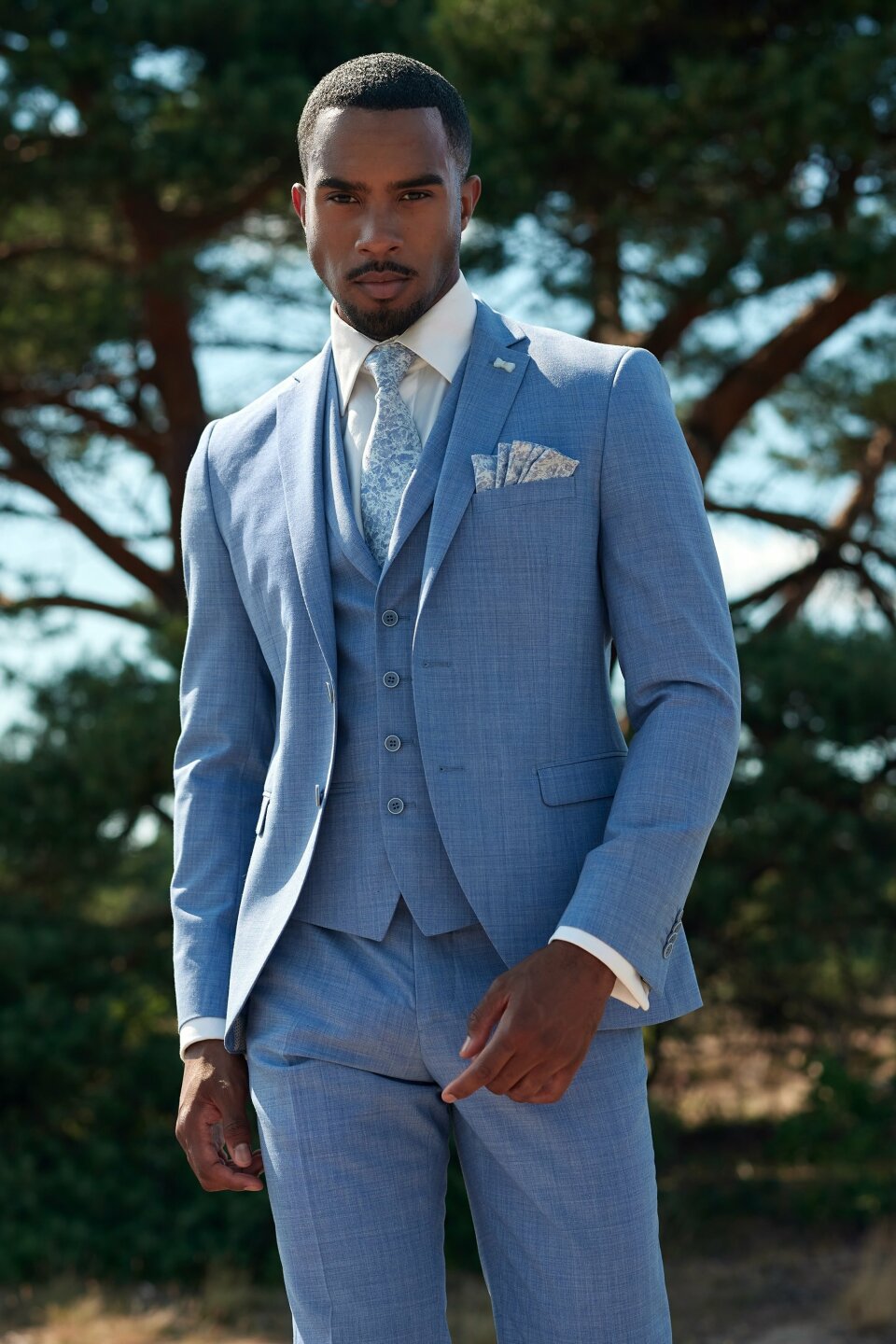 een man in een blauwe pak staand voor een boom