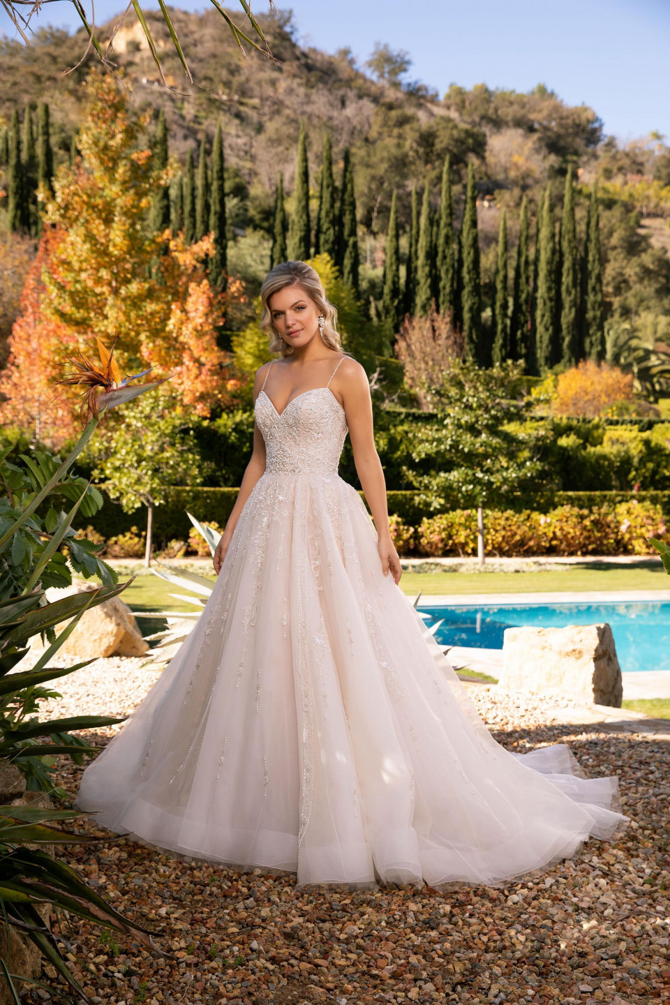 een mooie vrouw in een trouwjurk staat voor een zwembad