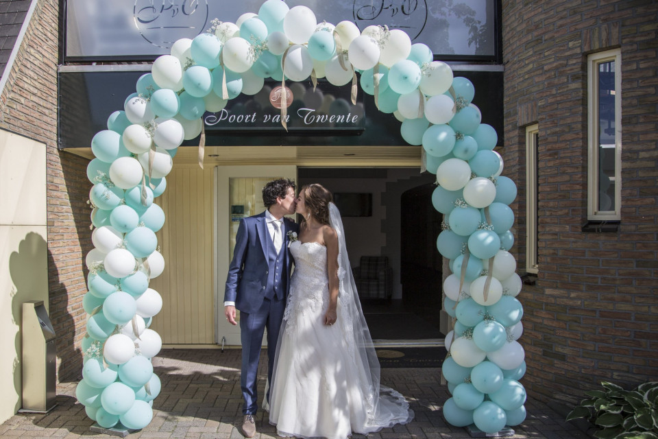 een bruid en bruidegom onder een boog van ballonnen