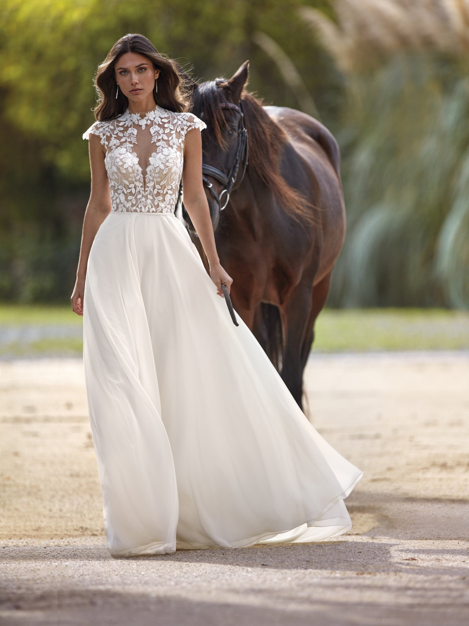 een vrouw in een trouwjurk die naast een paard loopt