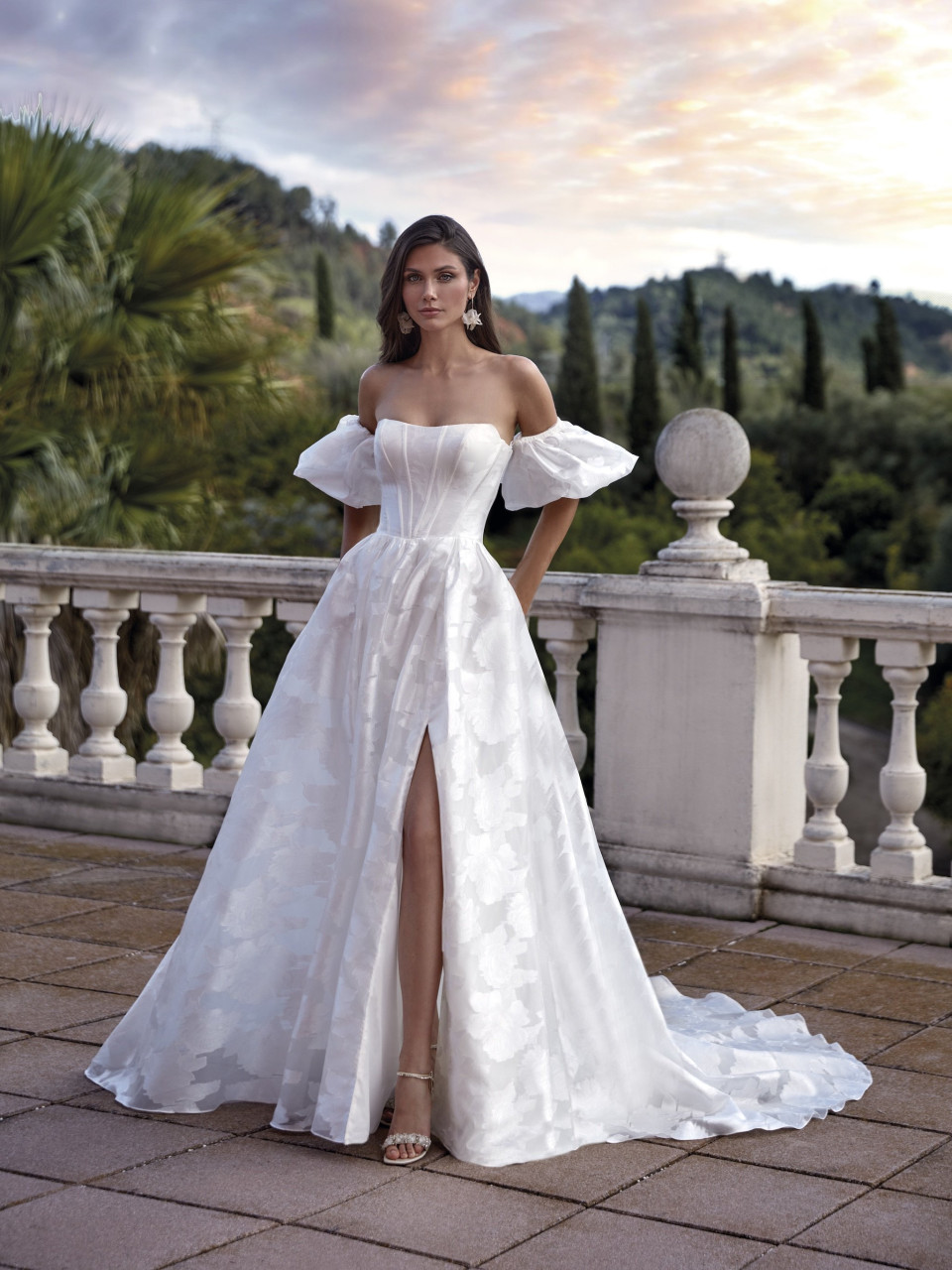 een vrouw in een trouwjurk die op een balkon staat