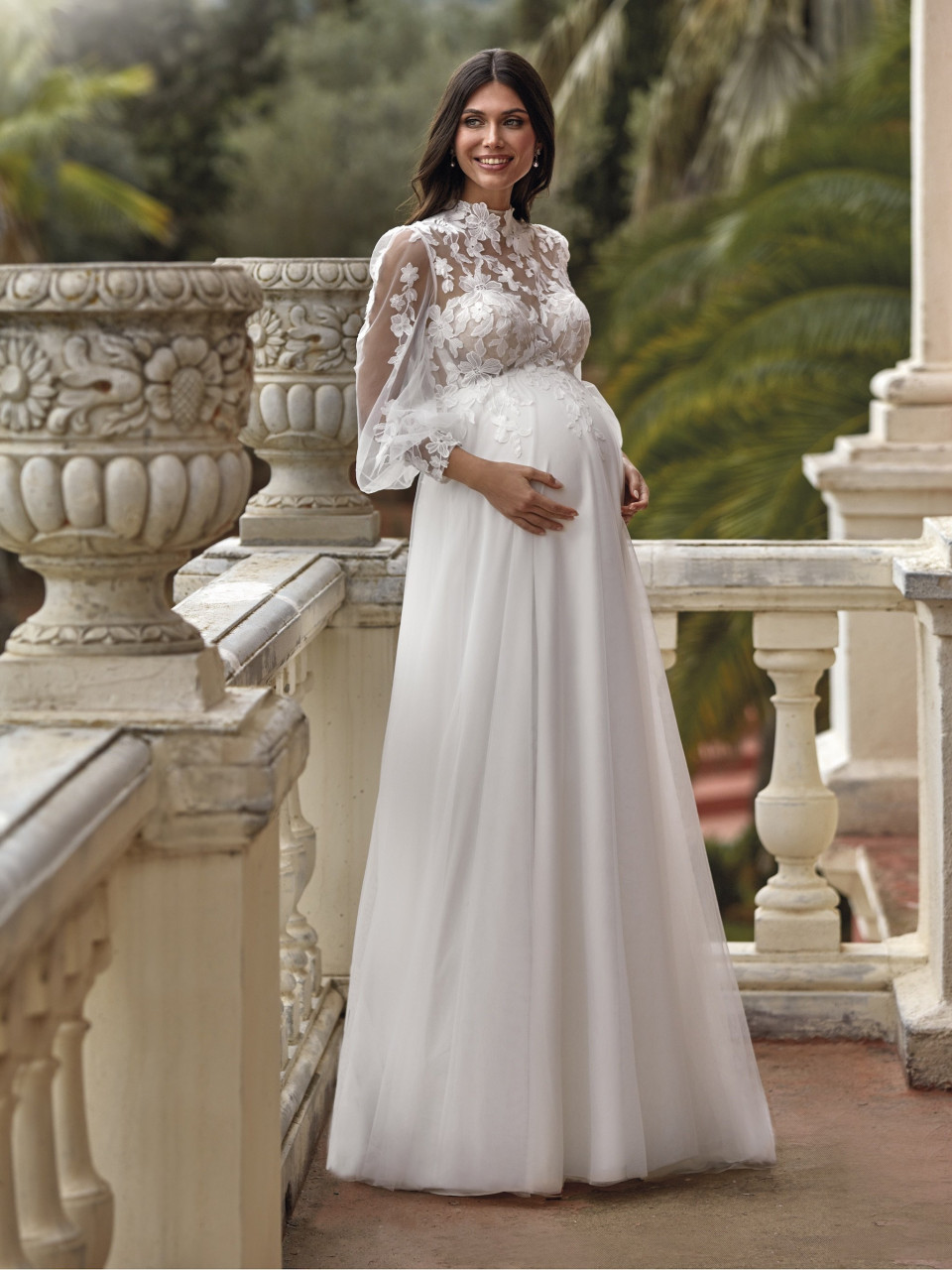 een zwangere vrouw in een witte jurk die op een balkon staat