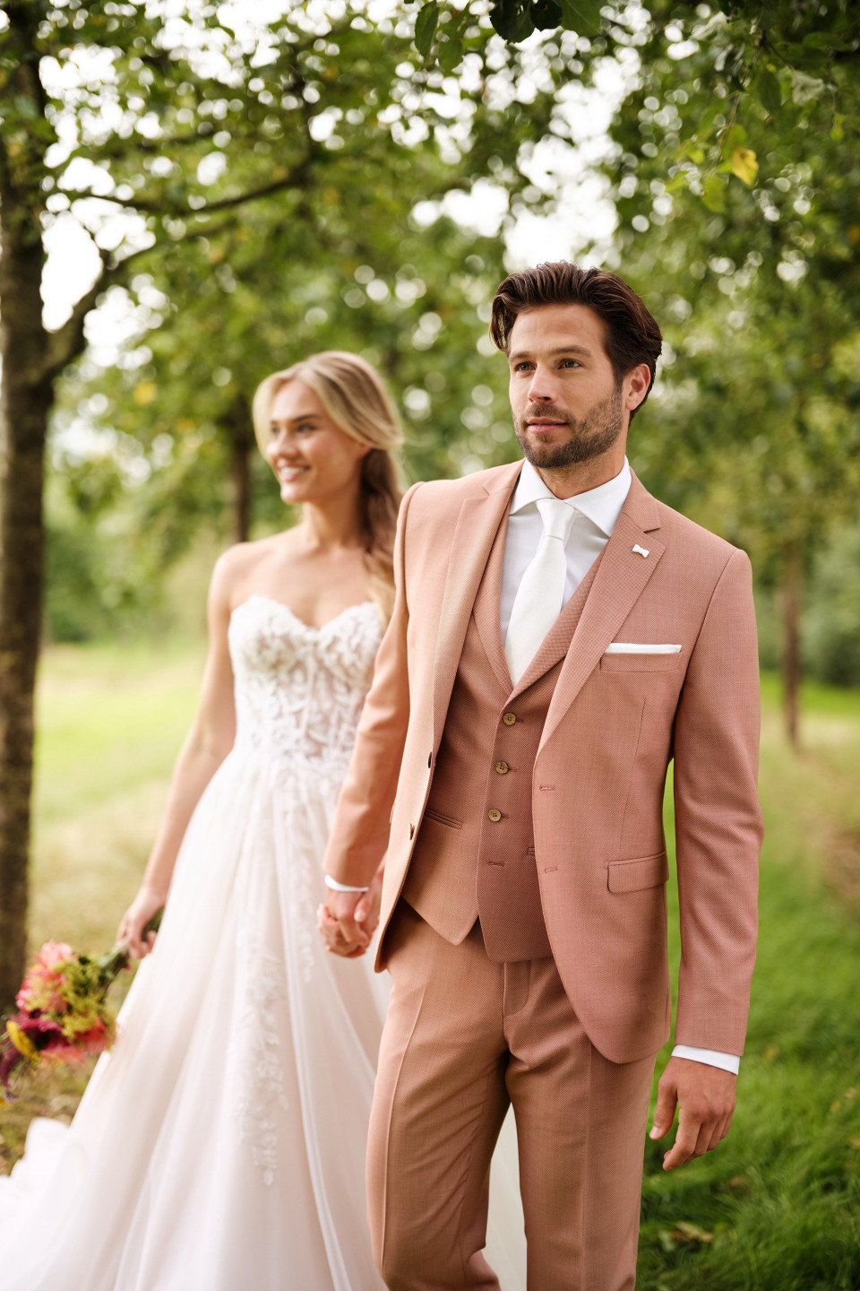 een man en vrouw in een trouwpak lopen samen