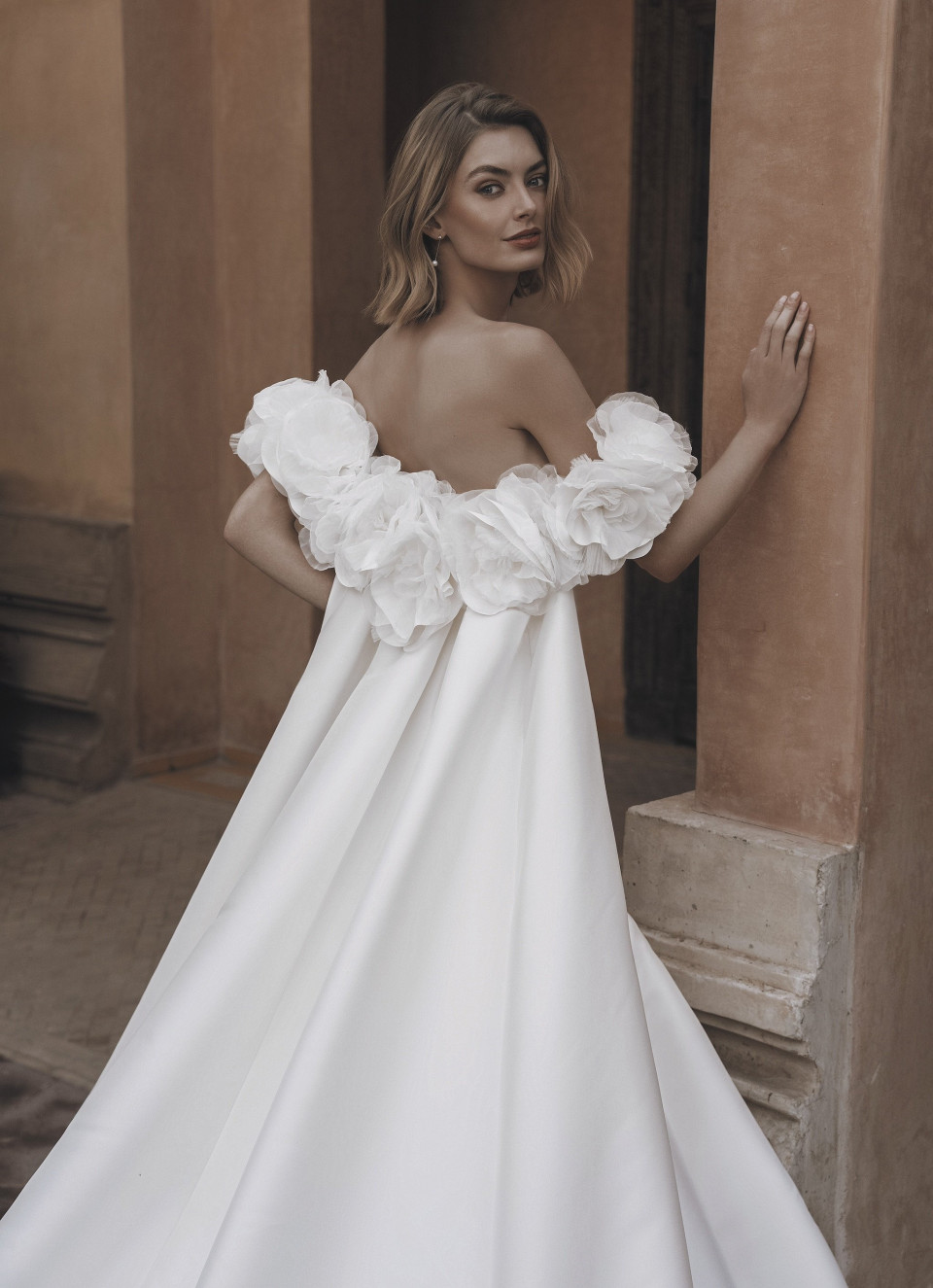 het model draagt een witte trouwjurk met een gerimpelde rok