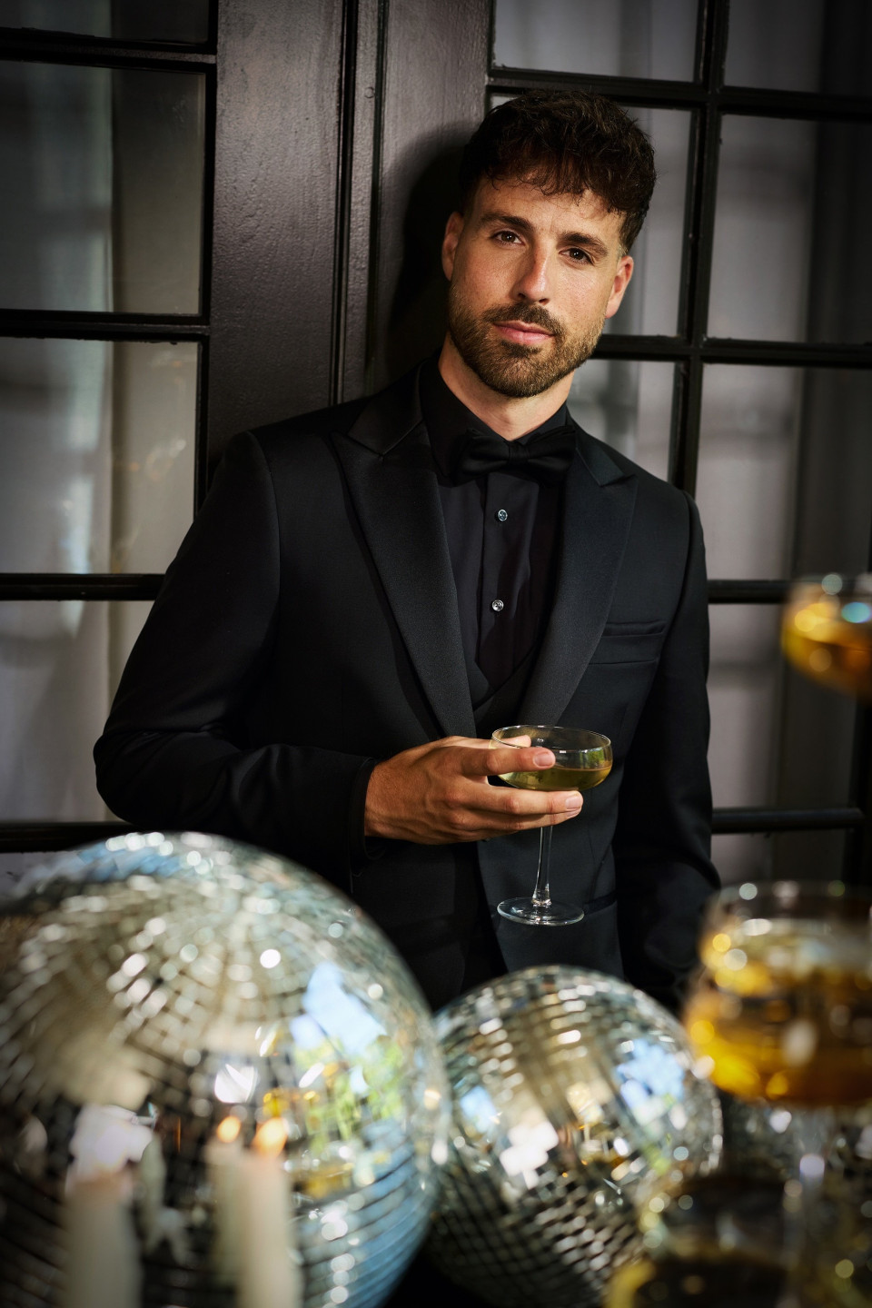 een man in een smoking die een glas wijn vasthoudt