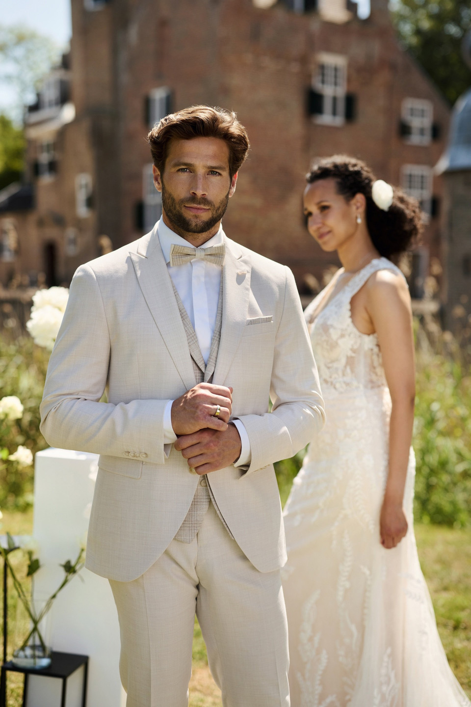 een man in een pak die naast een vrouw in een trouwjurk staat