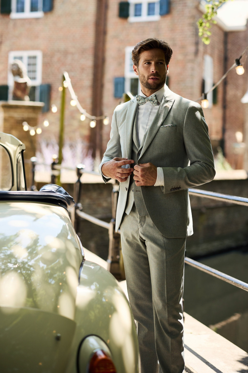 een man in een pak die naast een auto staat