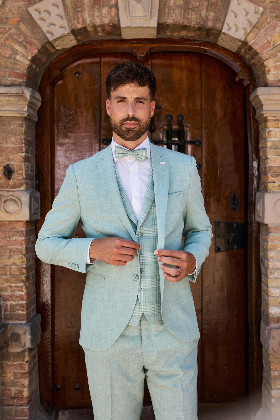 een man in een pak die voor een deur staat