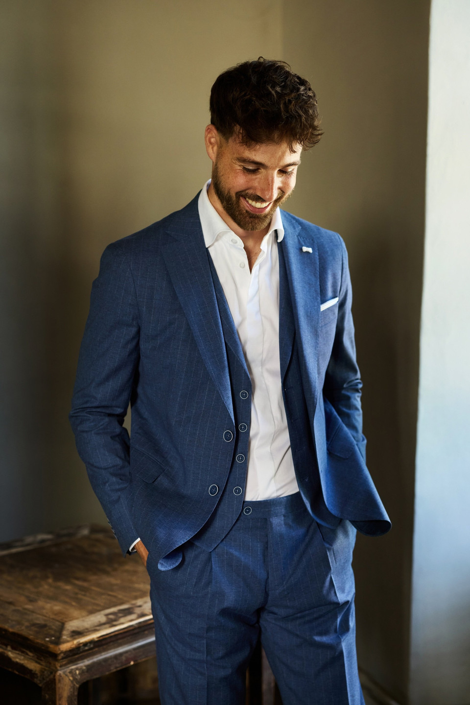 een man in een blauw pak die naast een houten tafel staat