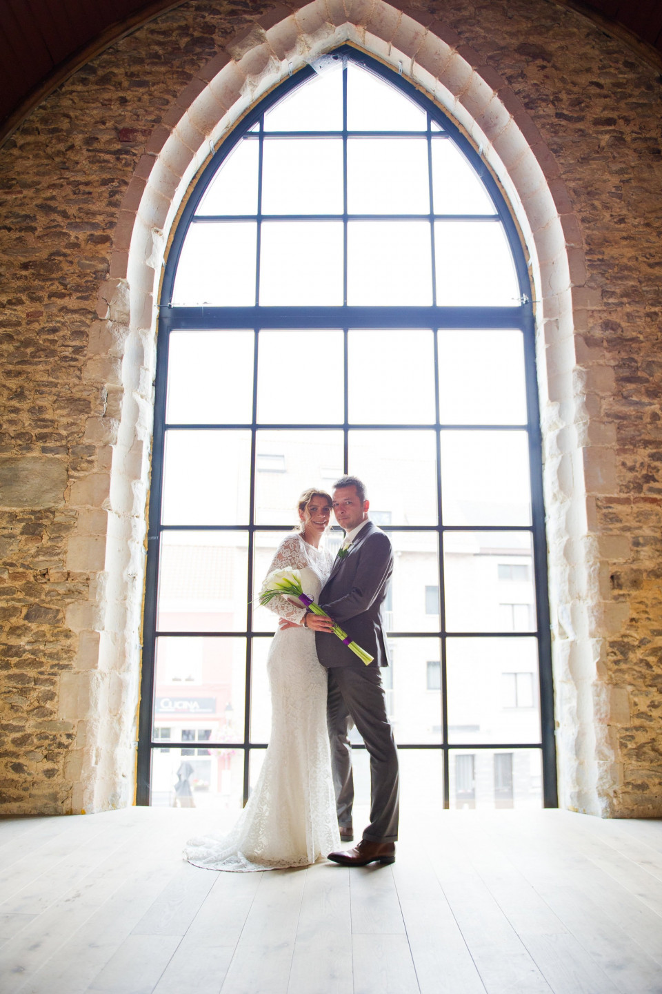 een bruid en bruidegom staan voor een groot raam