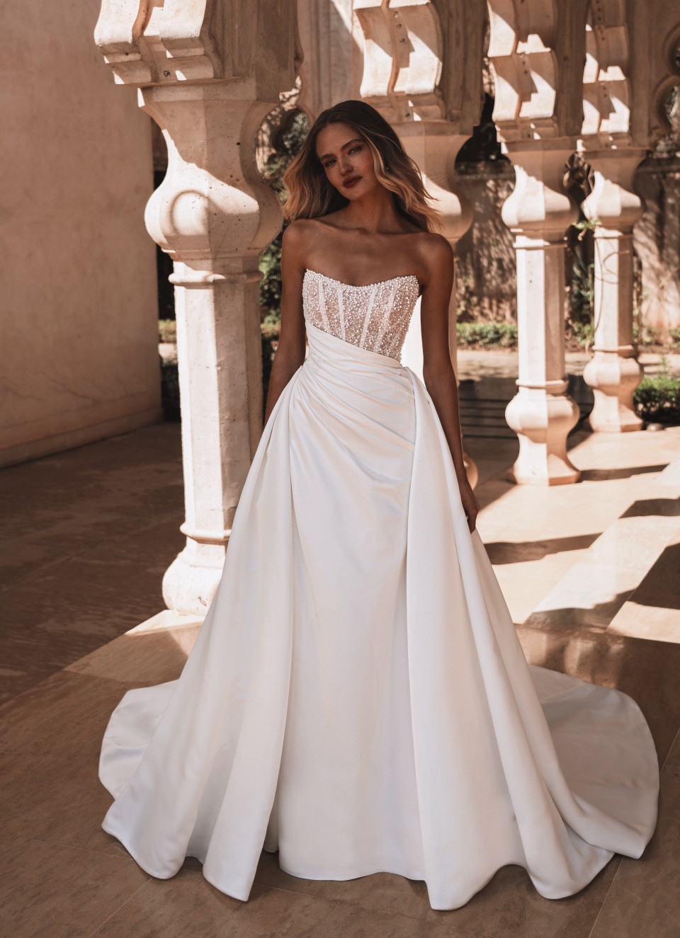 een vrouw in een witte trouwjurk poseert voor een foto