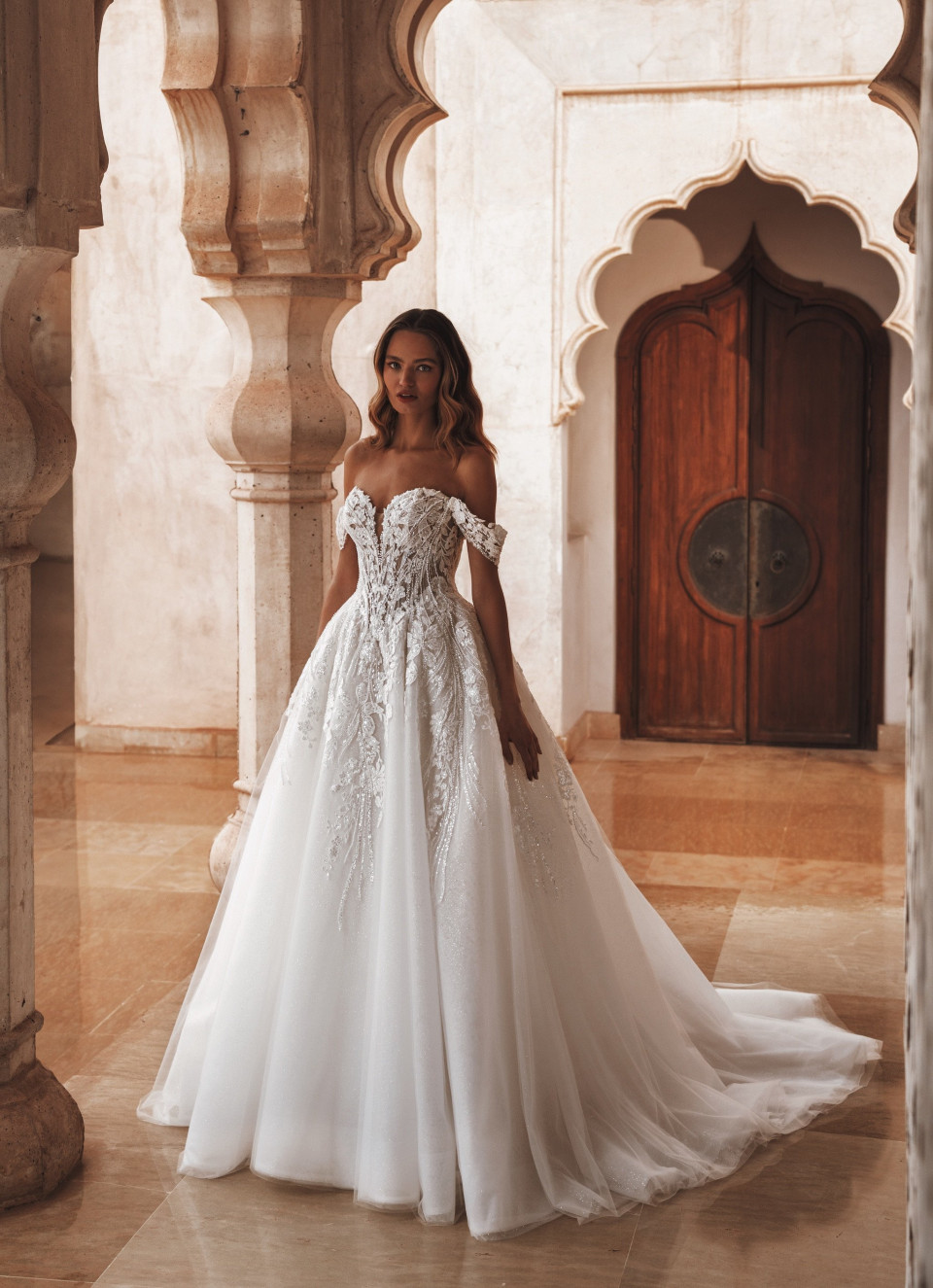 een vrouw in een trouwjurk staat in een boog