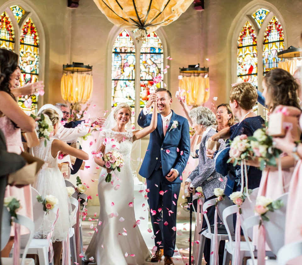 een bruid en bruidegom lopen door het gangpad met confetti