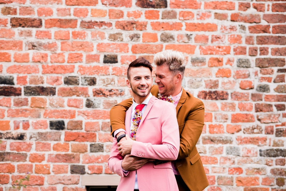 twee mannen in pakken omhelzen elkaar voor een bakstenen muur