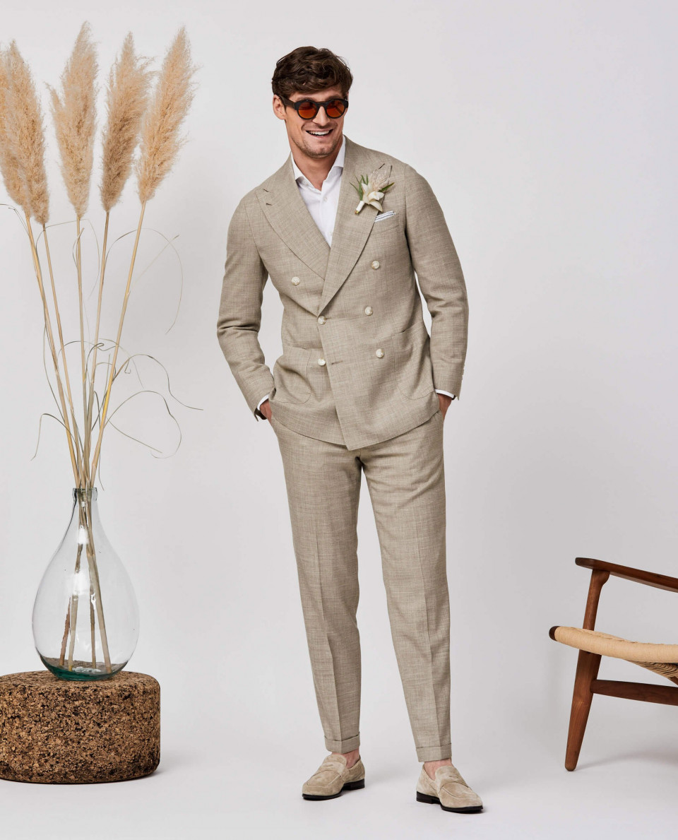 een man in een pak en zonnebril die naast een vaas staat