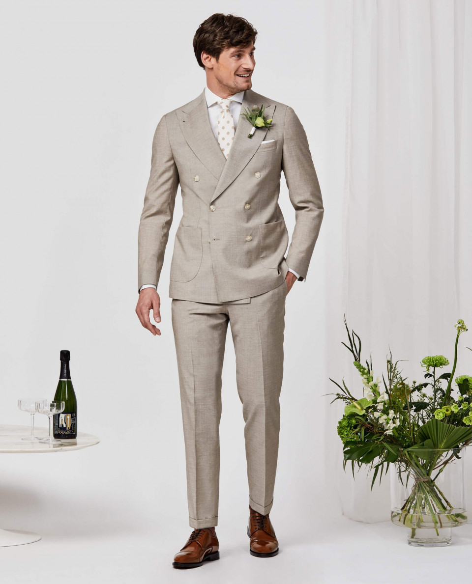 een man in een beige pak en wit overhemd