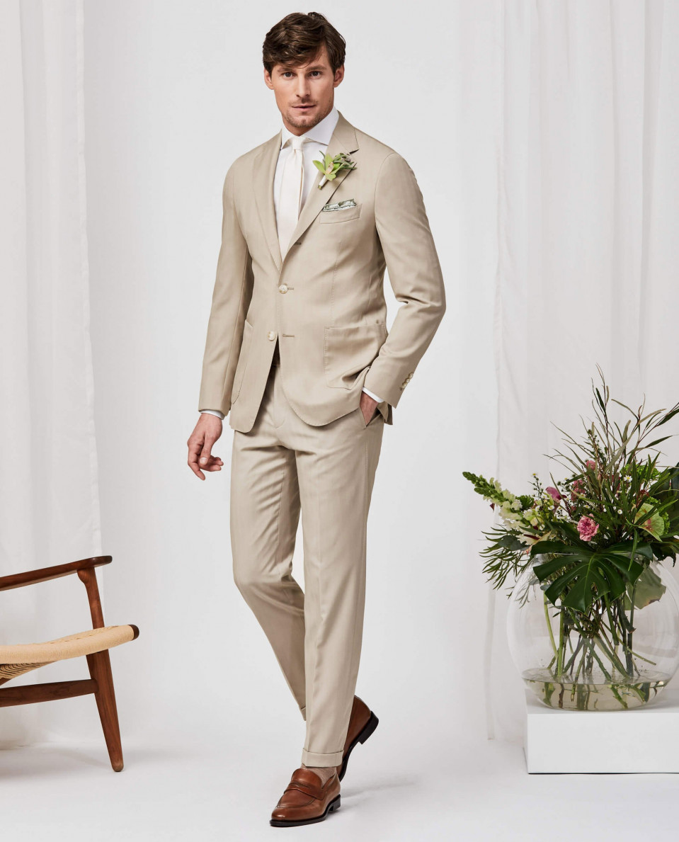 een man in een beige pak en schoenen