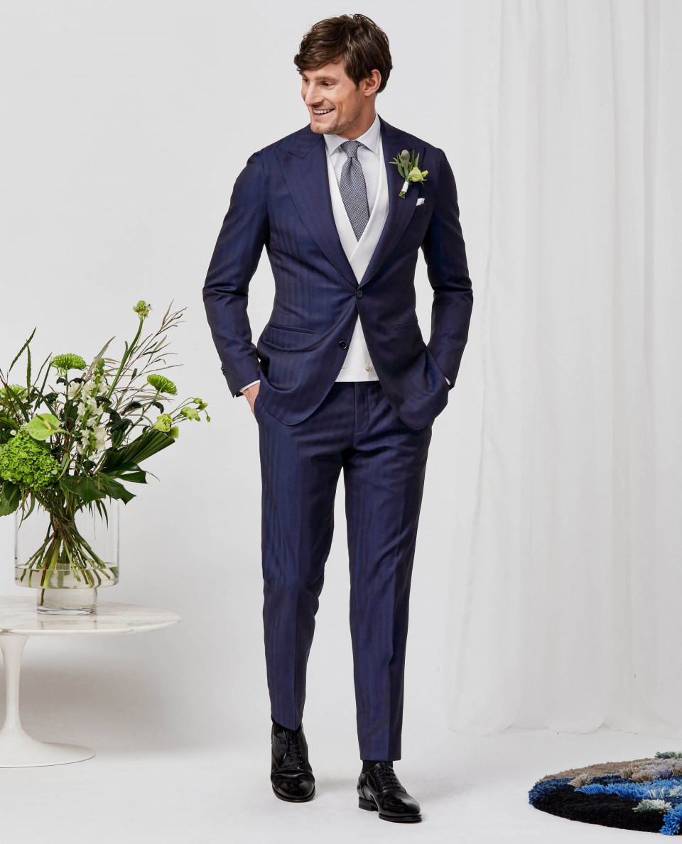 een man in een blauw pak en stropdas die voor een vaas staat