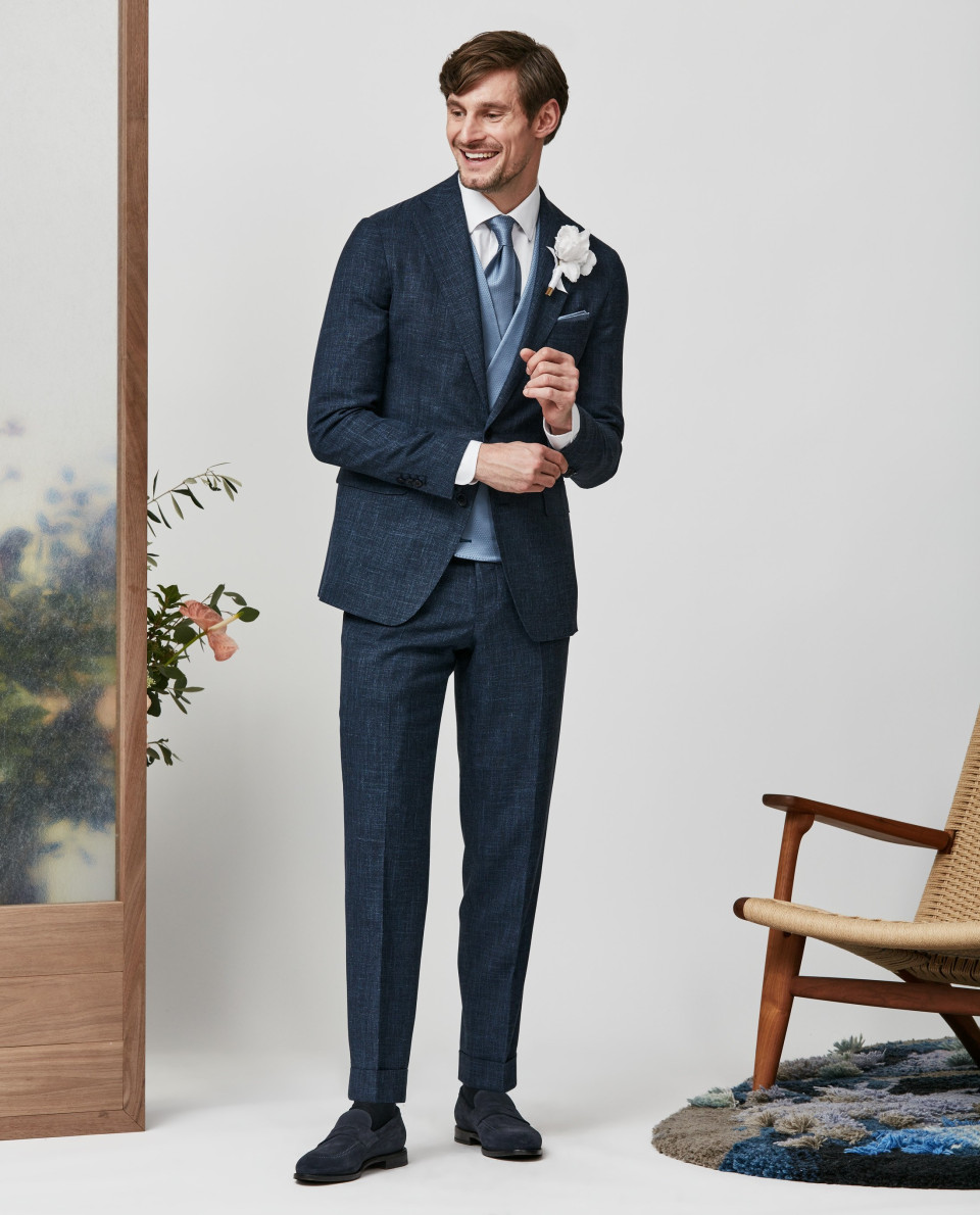 een man in een pak en stropdas staat voor een stoel