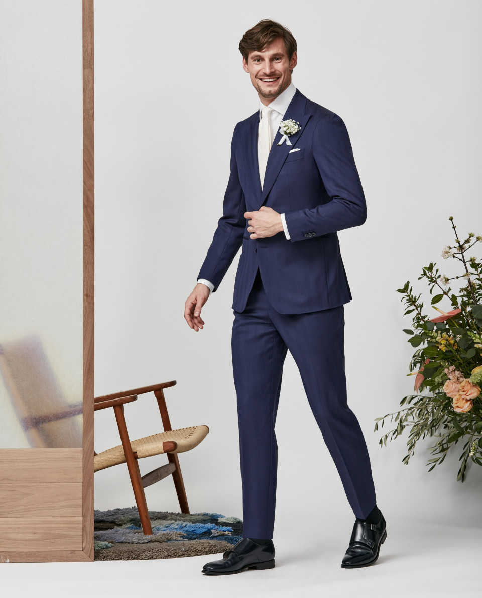 een man in een blauw pak en witte schoenen