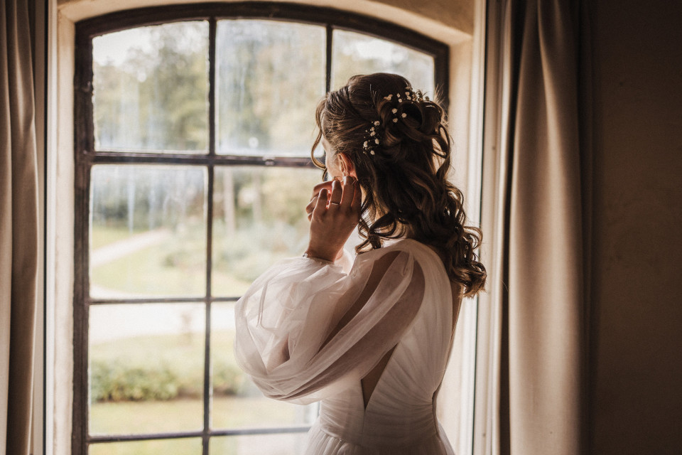 een bruid kijkt uit het raam naar de regen
