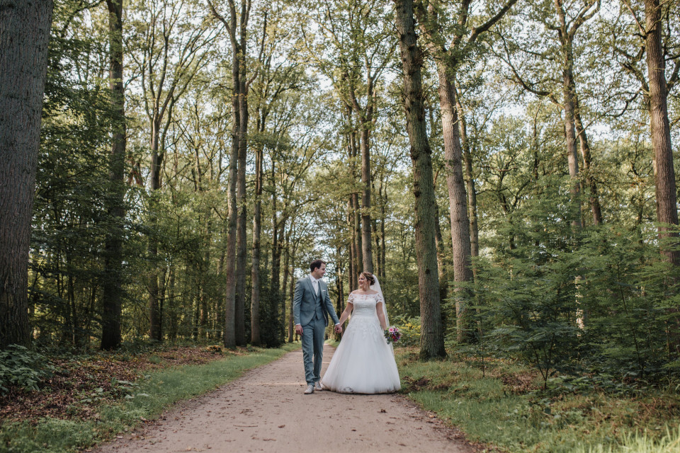 een bruid en bruidegom lopen door het bos