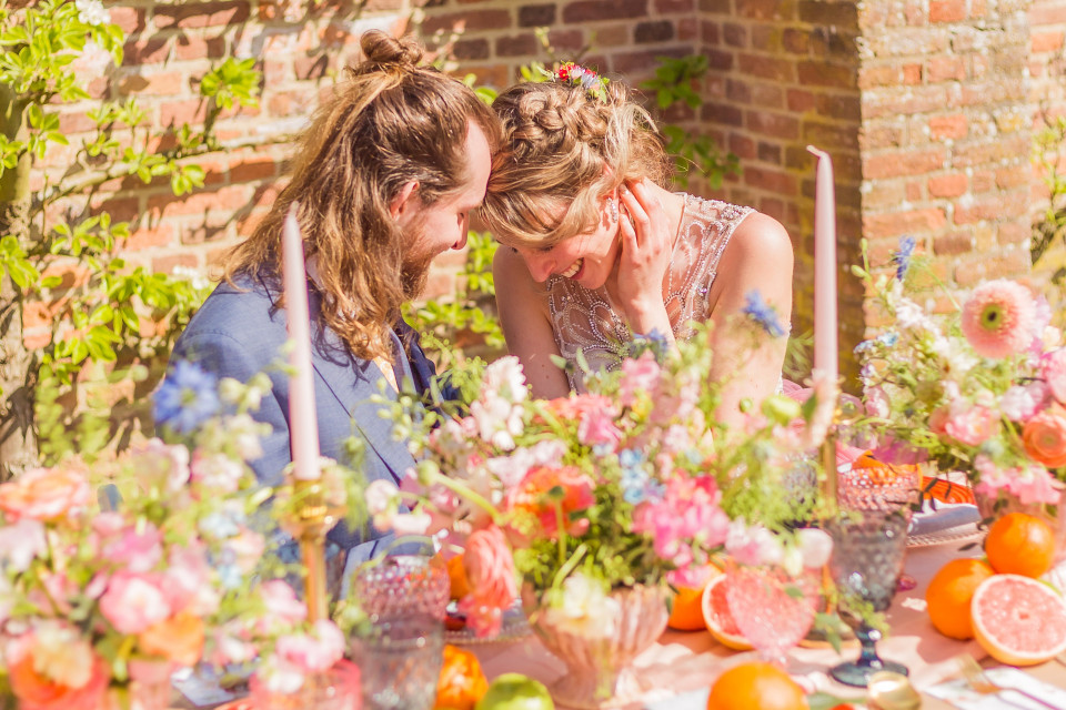 een bruid en bruidegom zitten aan een tafel met bloemen en fruit