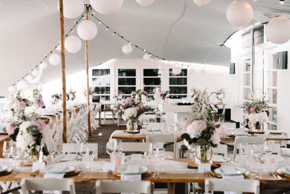 een bruiloftsreceptietent met witte en roze versieringen