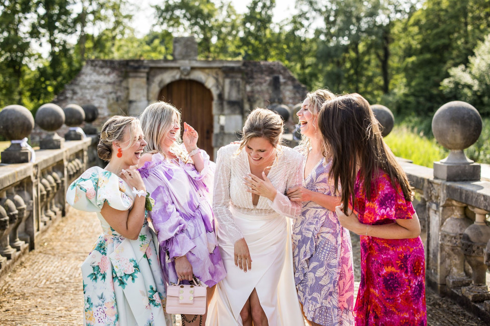 een groep vrouwen staat naast elkaar op een brug met een vrouw die haar gezicht met haar handen bedekt