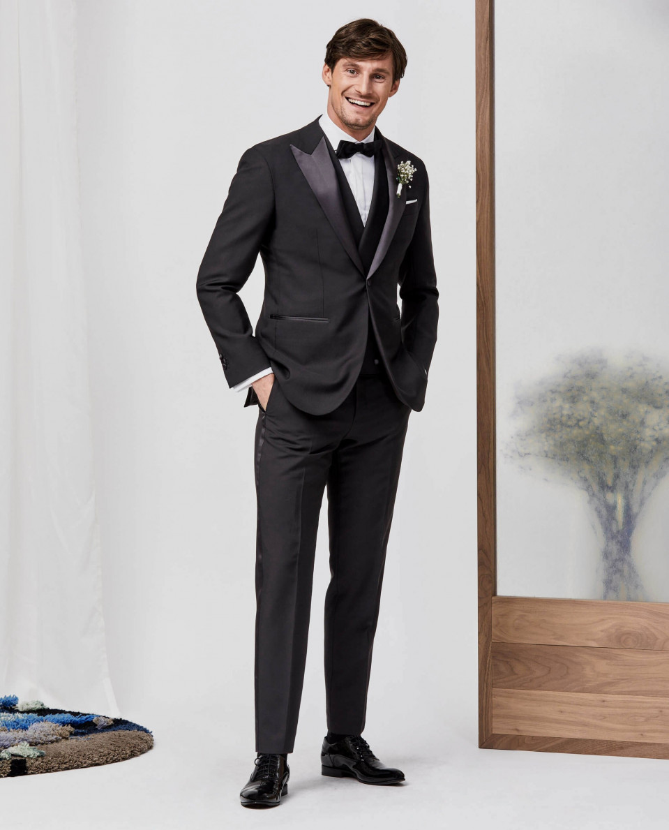 een man in een smoking poseert voor een foto