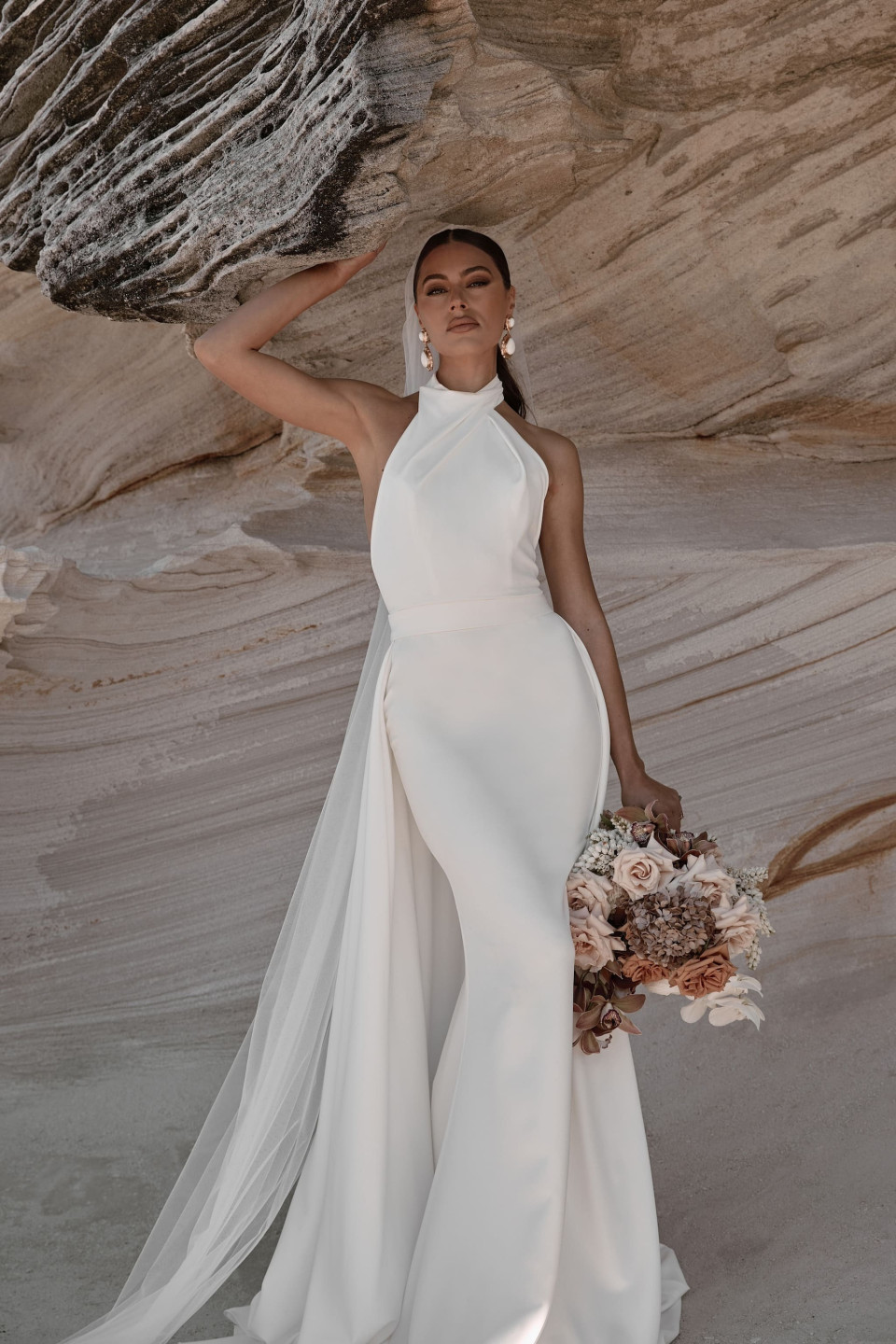 een bruid in een wit gewaad staat op een rots