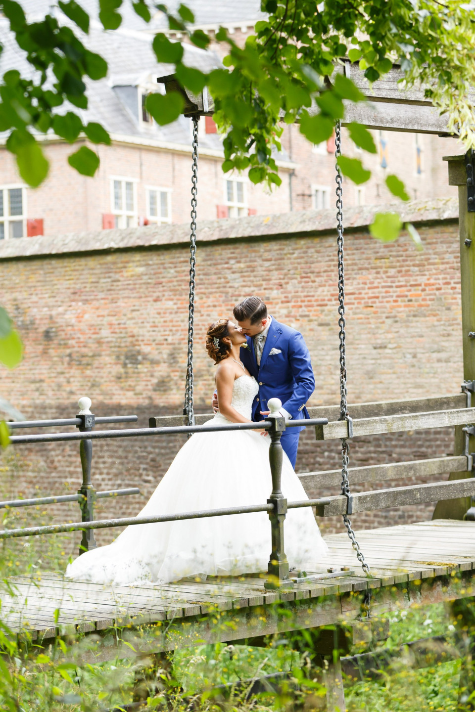 een bruid en bruidegom op een brug in het park