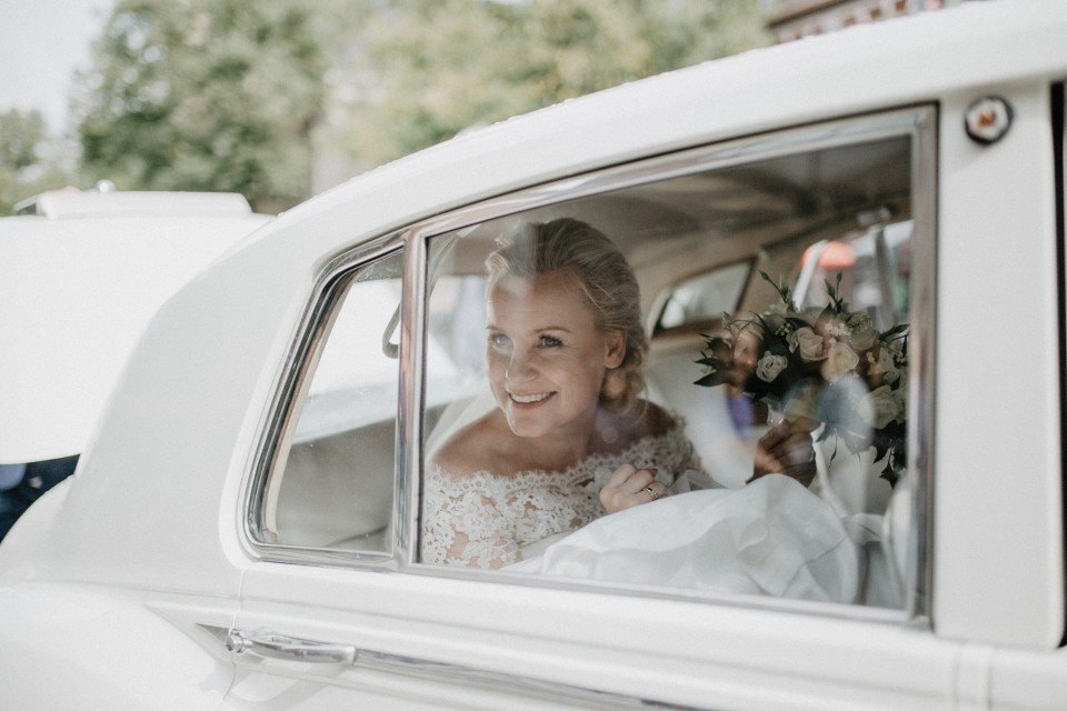 bruid in auto met haar boeket