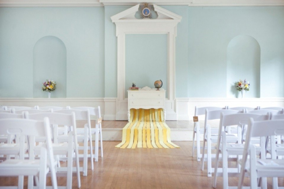 een trouwceremoniezaal met witte stoelen en gele vloerbedekking