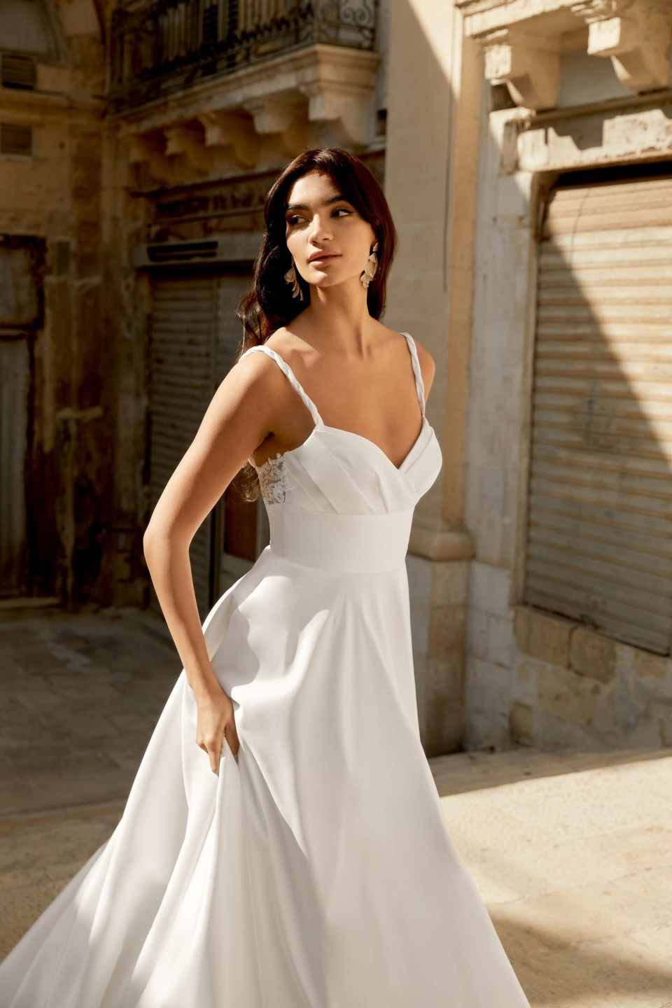 een vrouw in een witte trouwjurk die in een steegje staat