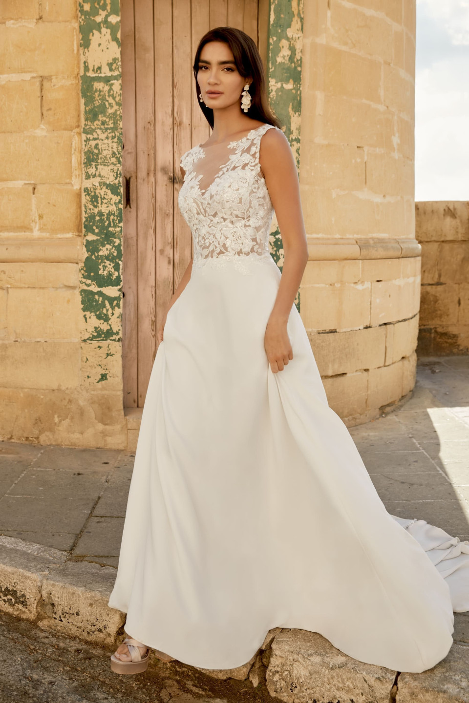 een vrouw in een trouwjurk die voor een oud gebouw staat