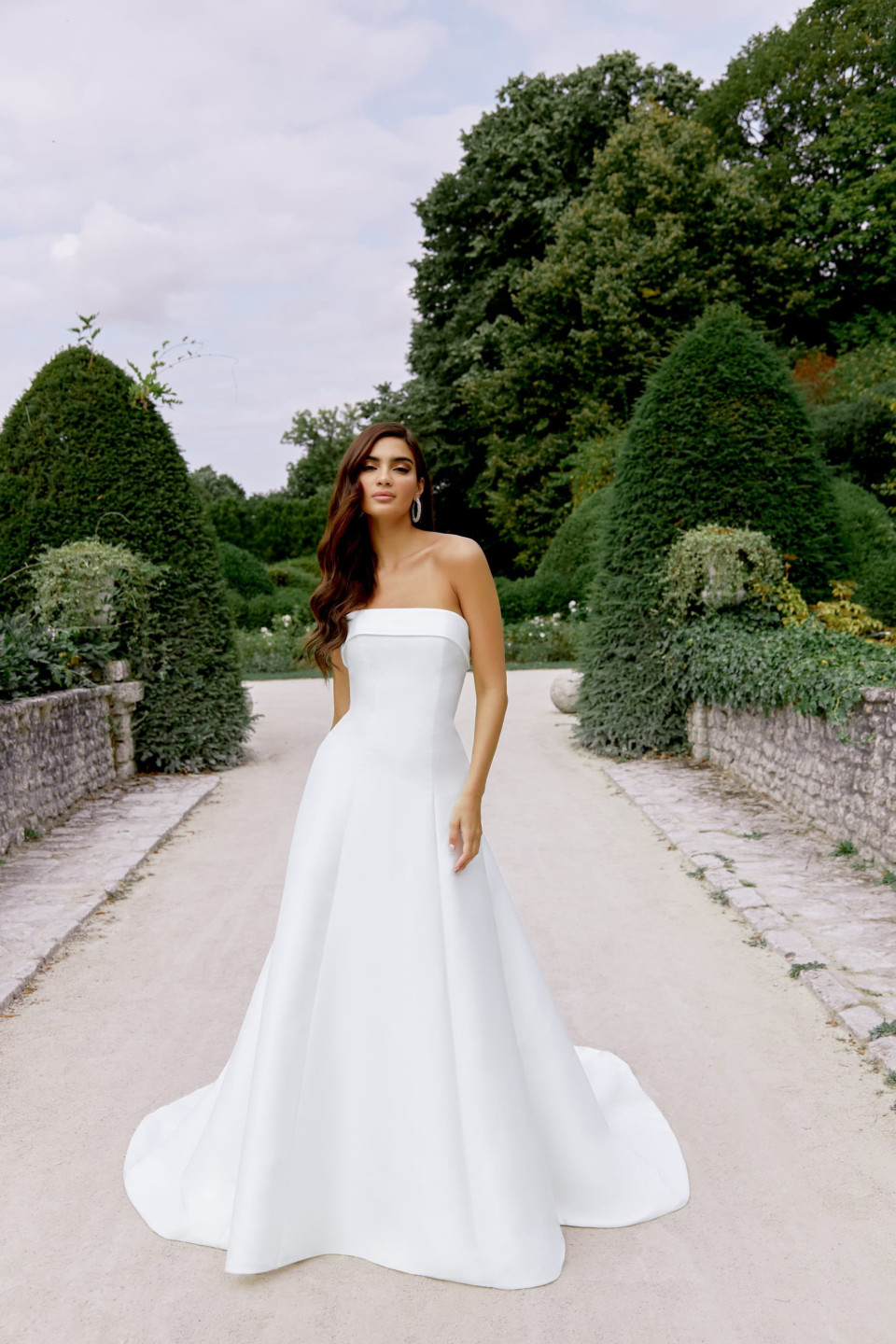 een vrouw in een strapless trouwjurk die in een tuin staat