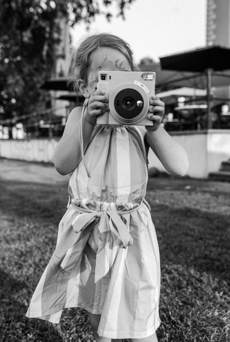 een zwart-wit foto van een klein meisje dat een foto maakt met een camera