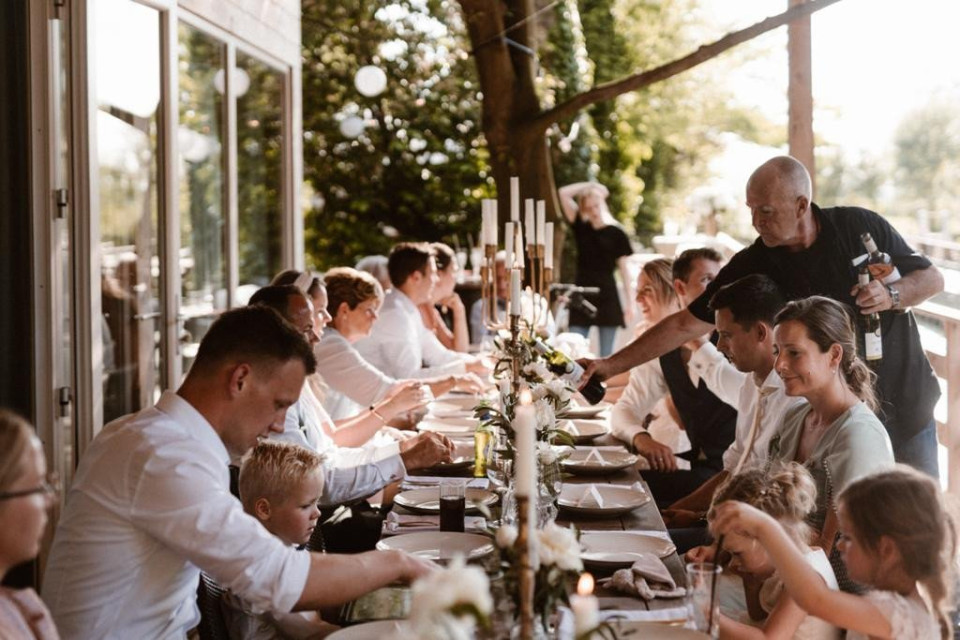 een groep mensen die aan een lange tafel zitten