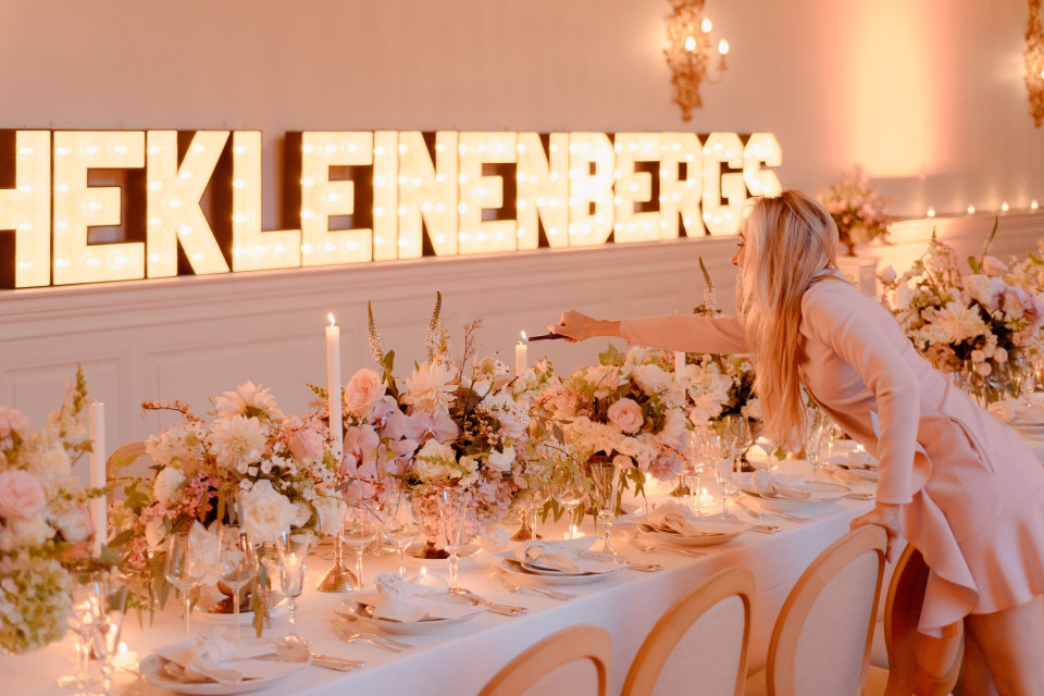 een vrouw in een roze jurk die een tafel voor een bruiloft klaarmaakt