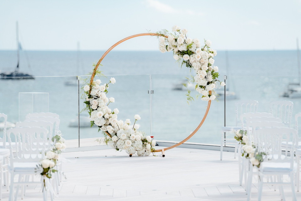 een bruiloftsceremonie met witte bloemen en een ronde boog
