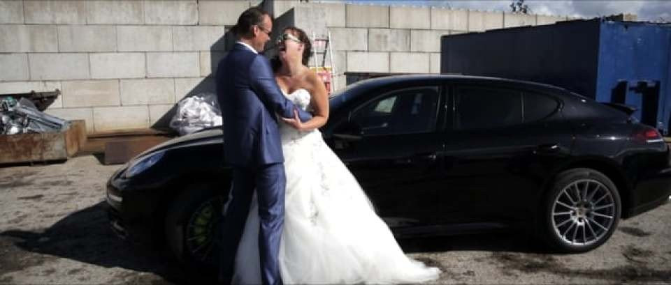 een bruid en bruidegom staan naast een zwarte auto