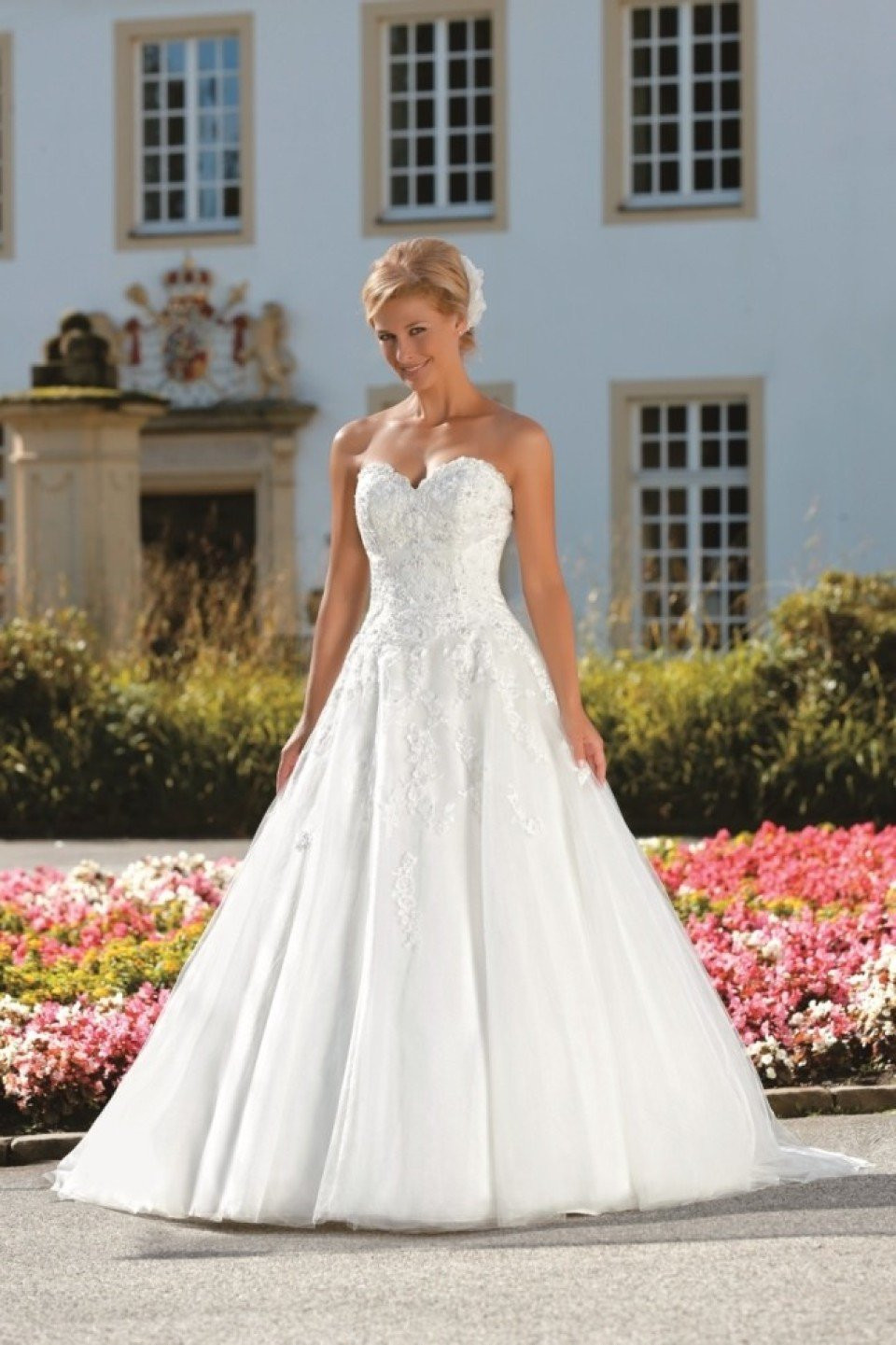 een prachtige bruid in een trouwjurk die voor een groot gebouw staat