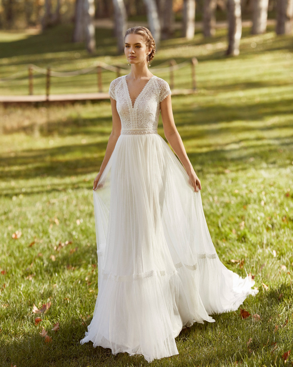 een vrouw in een trouwjurk staat in het gras