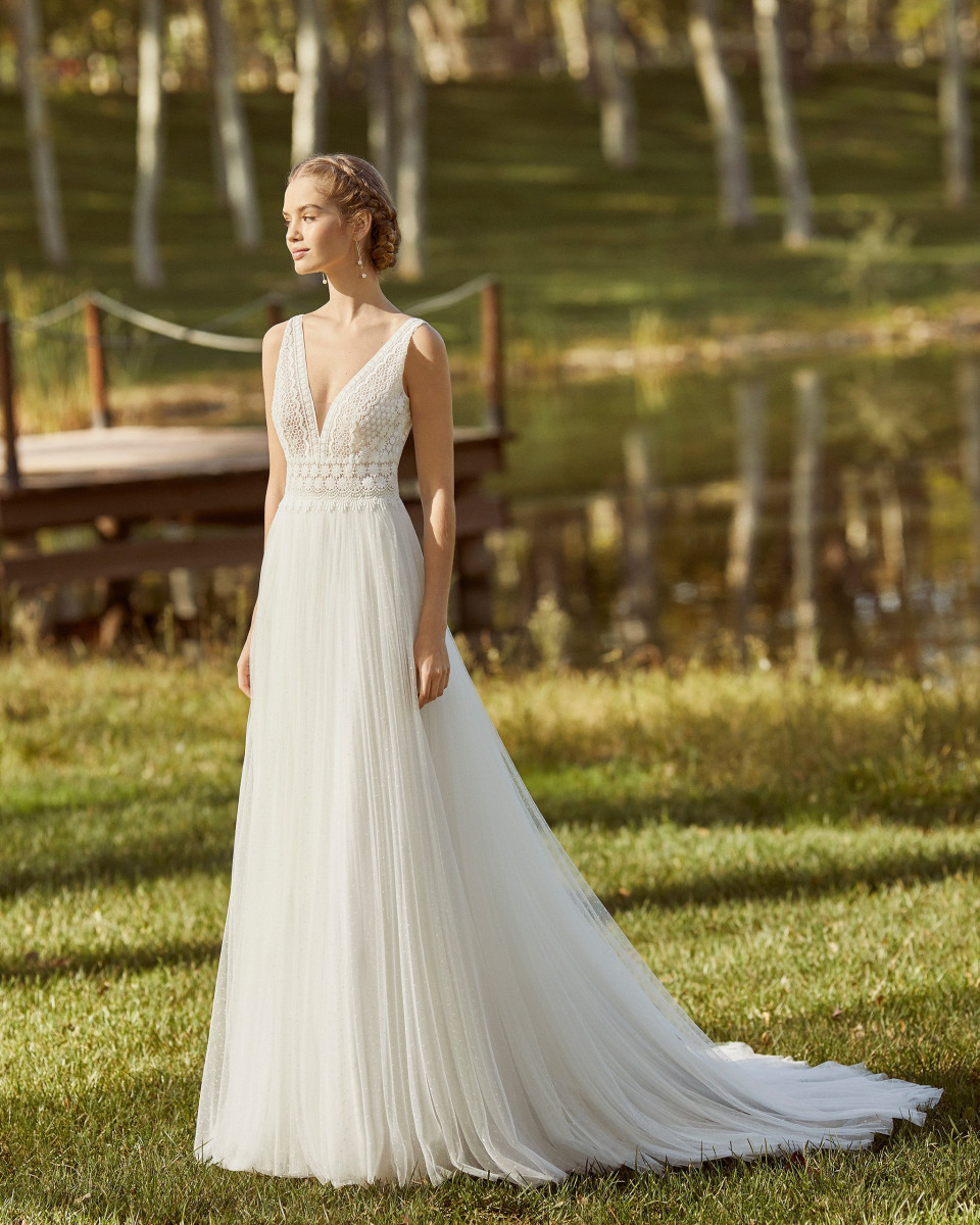 een mooie bruid in een trouwjurk die bij het meer staat