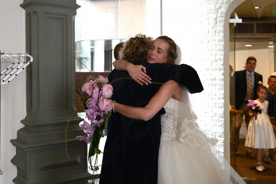 een bruid omhelst haar moeder terwijl ze door het gangpad loopt