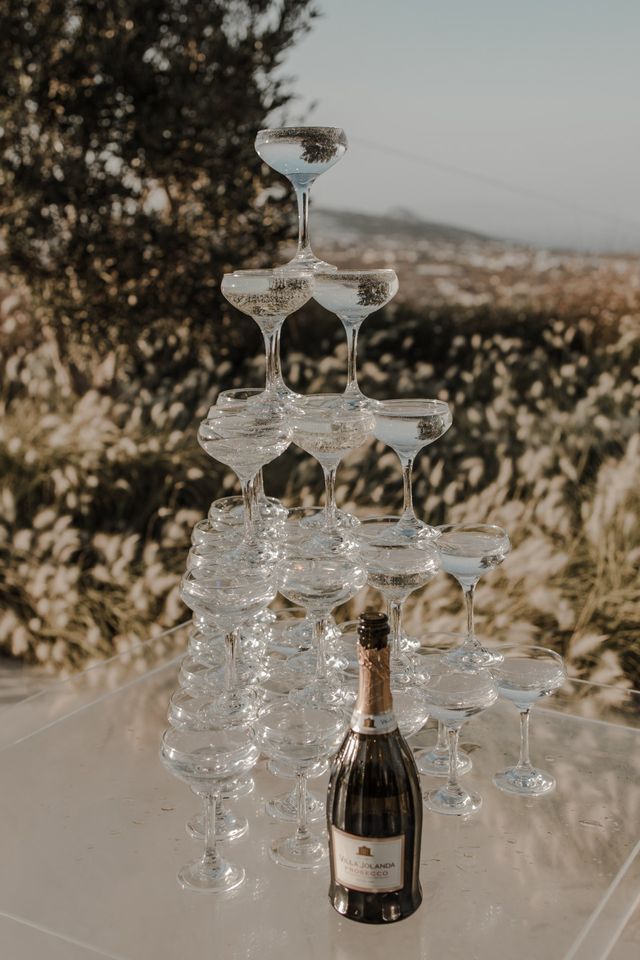 Champagne tower with a bottle at its base set against an outdoor view