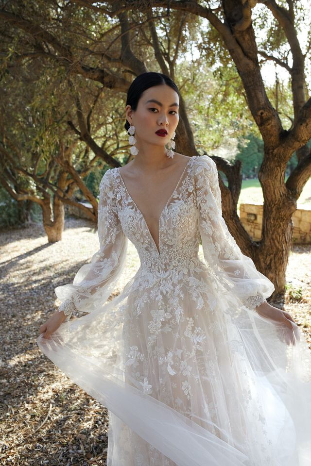 Braut in einem langärmligen Brautkleid in der Farbe Blush welches bestickt ist mit Glitzernden Blumen