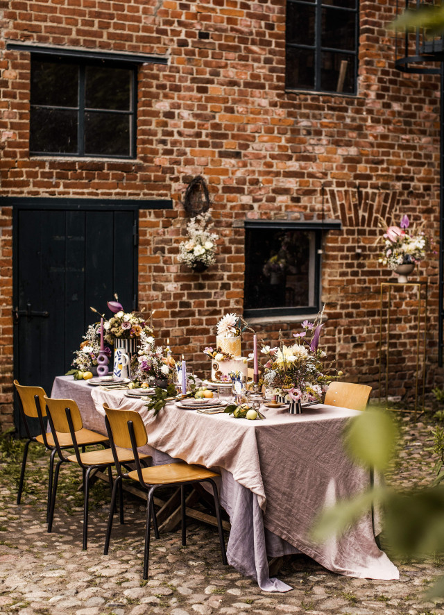 Gedeckter Hochzeitstisch mit lila Tischdecke in einem Hof