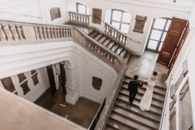 Brautpaar läuft eine Treppe in weißem Gebäude hoch